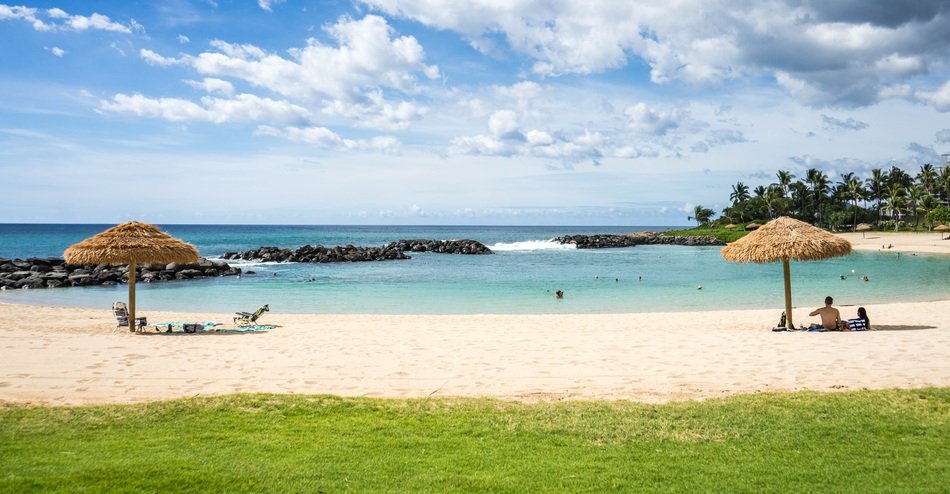 Beautiful sandy beach with people near the grass of Ko Olina Resort in Hawaii