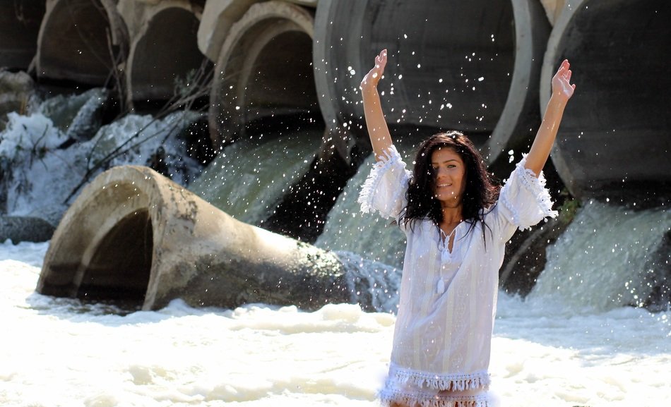 brunette girl in a spray of water near the water cascade