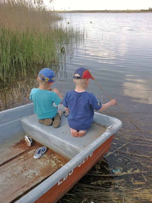 children sit on a boat by the river