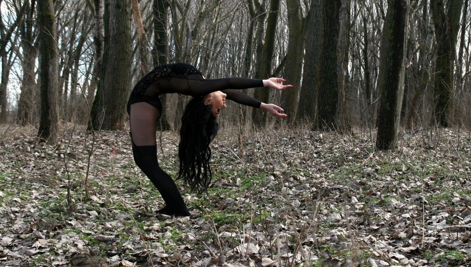girl is doing gymnastics on the background of the autumn forest