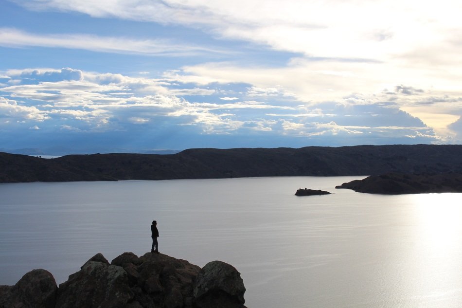 man on a rock near lake titicaca