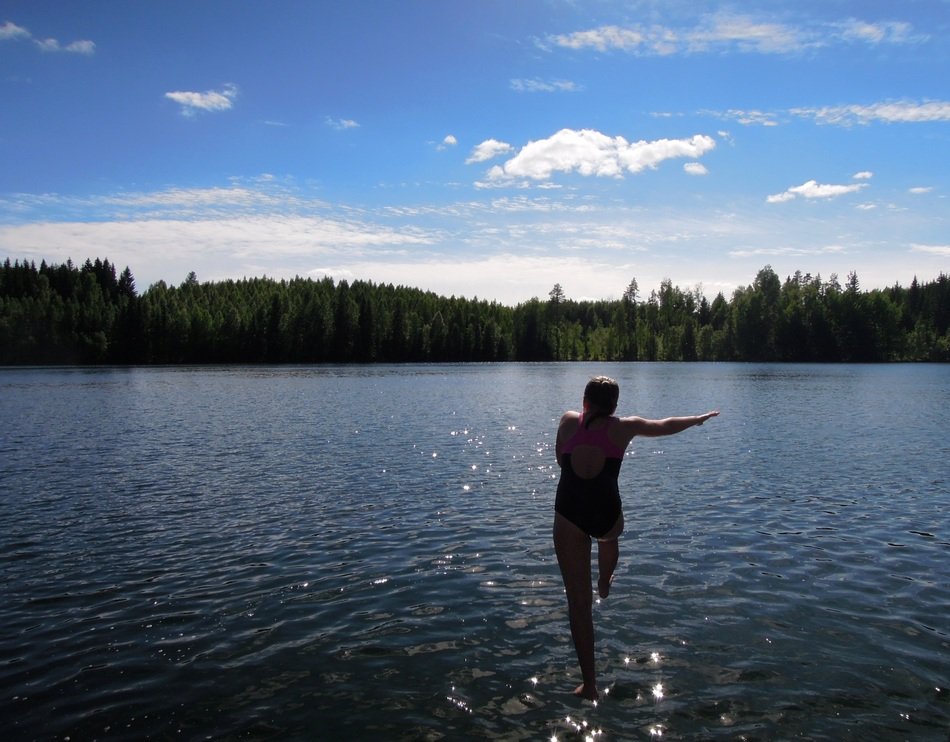girl with a run jumps into the Finnish lake