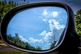 white clouds reflected in the side rearview mirror