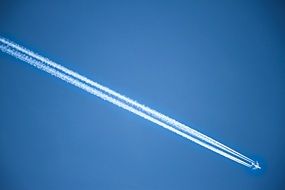 white trail from an airplane in the blue sky