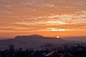 orange sunrise and bright sun on a city plain