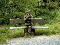 wooden bench with sculpture in the park