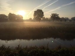 sunrise over rural field and pond