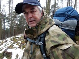 portrait of senior man with backpack in winter forest