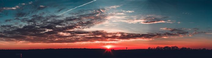 distant view of red sunset in the cloudy sky