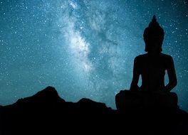 silhouette of a large Buddha statue on the background of the Milky Way