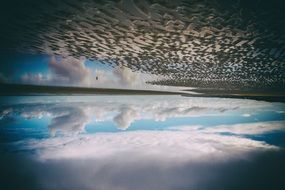 mirror reflection of blue sky with clouds on the ocean