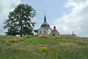 Landscape of green mountain with plants and colorful church on background