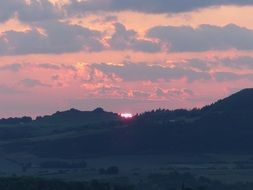 pink sunrise in the clouds over the hills
