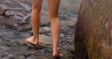 Barefeet Person stands on stones in water