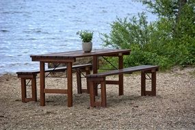 benches and wooden table with potted plant by the lake