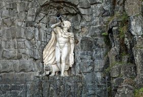 sculpture of a young man with a pipe in the wall in a mountain park in Kassel