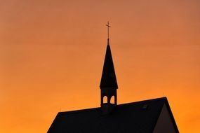 silhouette of church tower on orange sky background