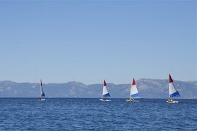 Sailboats with flags on Lake Tahoe at background with mountains