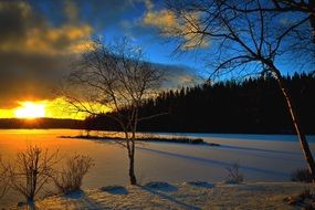 Distant view of the beautiful yellow sunset over a snowy lake in winter in Quebec, Canada