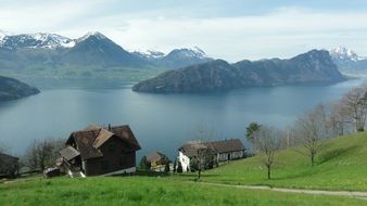 Houses and a pond at the foot of the snowy mountains on beautiful landscape in Switzerland