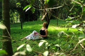 girl sitting on the green grass near the tree