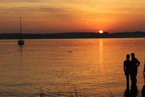 couple in love stands on the lake at sunset