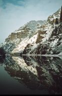 scenic rocks covered with snow mirroring on water, Glenwood Canyon on Colorado River, usa