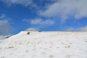 Landscape of the beautiful hill in snow under blue sky with white clouds
