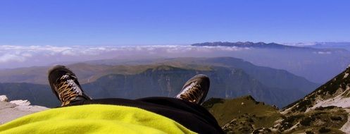 photo of the feet of a tourist resting on top of a mountain