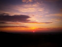 distant view of colorful sunset in dark clouds