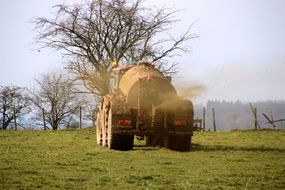 large tractor with manure in a green meadow