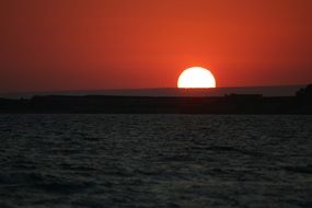 scarlet sunset and white sun on the horizon