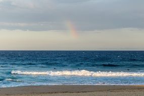 distant view of a beautiful colorful rainbow over a beach in New South Wales