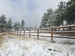 Wooden fence along winter Snowy field, america