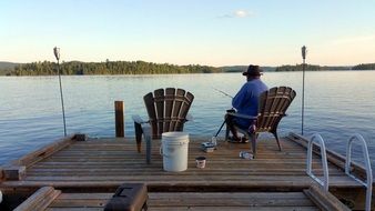 fisherman in a beach chair on a wooden pier