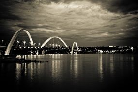 Back and white photo of the illuminated bridge with the lights over a lake in brazil