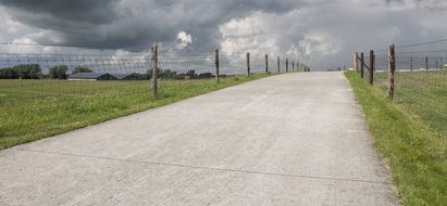 Landscape of asphalt road along the fenced field