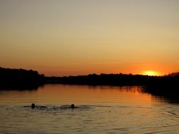 People in the lake near the trees under the sunset in Poland