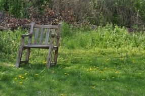 wooden old chair on green grass in the meadow