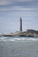 photo of high waves against the background of a lighthouse
