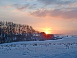 distant view of the evening sun over a winter landscape