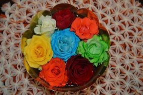 bouquet of different roses in a vase on a lace napkin