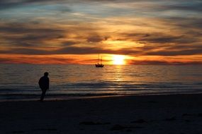 silhouette of a man by the sea on a background of colorful sunset