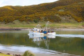 fishing boat floating on the river along the hills