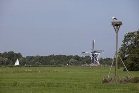 Stork near the mill and sailing boat