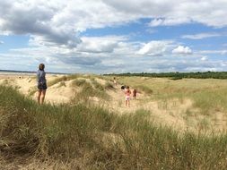 people among sand dunes in green grass