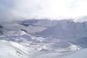 distant view of Skiing people on Snowy Mountains beneath clouds