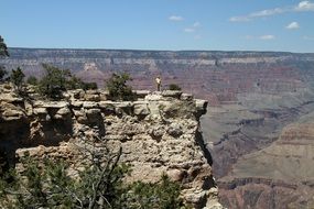 distant view of man on a cliff above the grand canyon