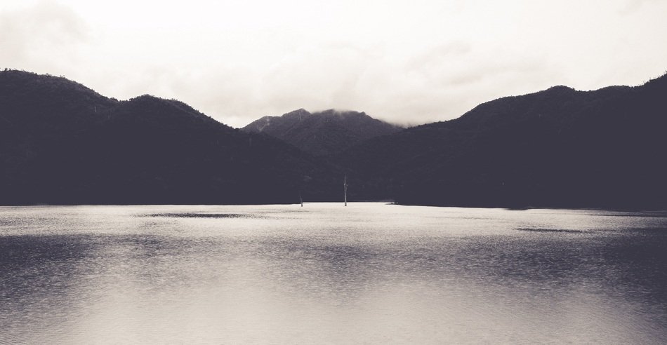 lake between hills in black and white image