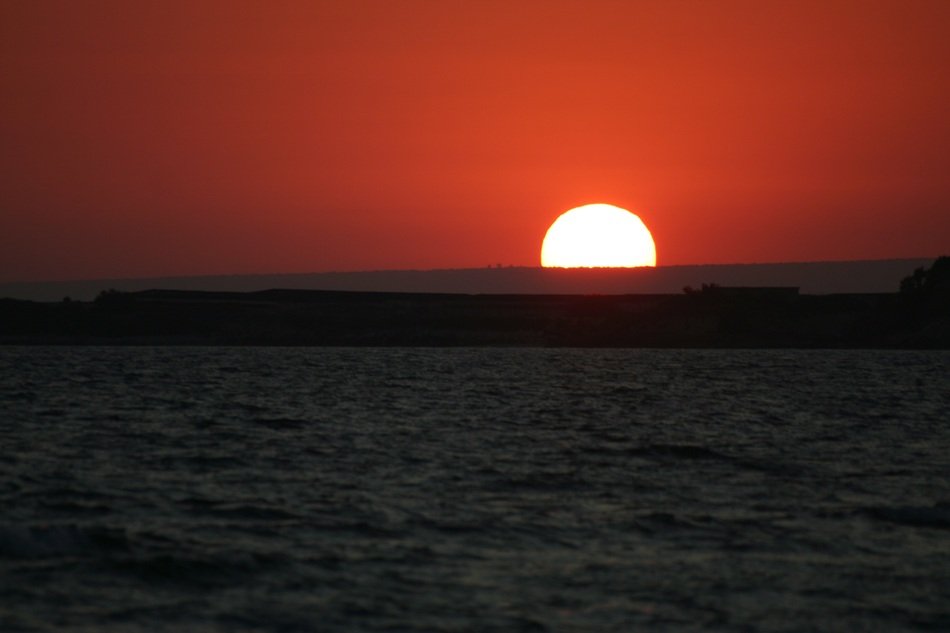 scarlet sunset and white sun on the horizon